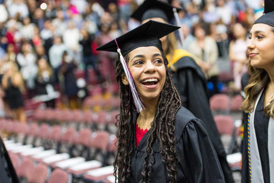 A young woman smiles in academic regalia at her graduation ceremony.