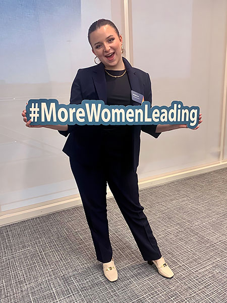 woman holding a sign that says 'More Women Leading'