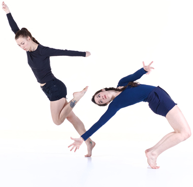Two dancers wearing dark colors in modern dance poses