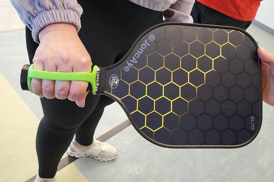 hand with adaptive grip holding a pickleball paddle