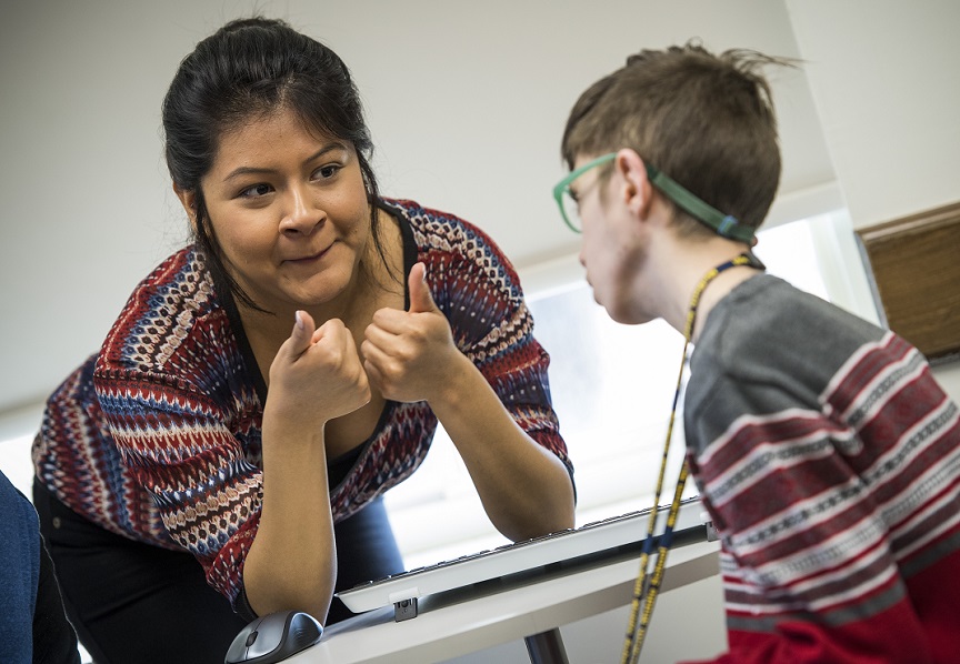 TWU students gives thumbs up to child in speech-language hearing lab.