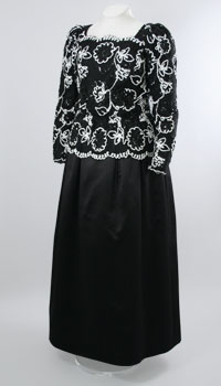 A black mid-length dress with long sleeves and white embroidery along the top half of the dress.