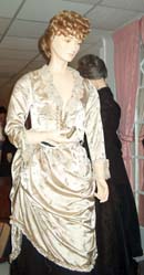 An ivory satin brocade dress draped over a black satin skirt on a mannequin.