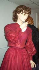 A long-sleeved red dress with a V-neck and tight bodice shown from the waist up. 