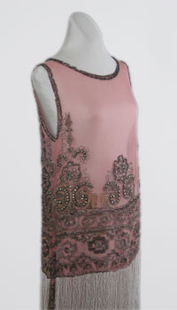A sleeveless orchid colored dress with floral embellishments and a fringe trim along the bottom.