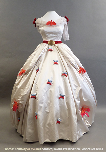 White satin dress with scattered red flowers on the skirt and a red velvet belt at the waist.