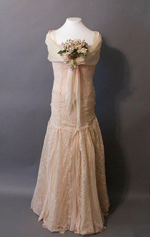 A pink lace gown with a fitted bodice and fun skirt. A deep fichu covers the shoulders.