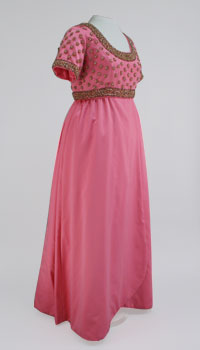A rose colored satin gown with a straight skirt, beaded bodice, short sleeves, and rounded neckline.