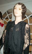 The dress shown from the waist up. Made of black satin brocade with a cowl drape at the neckline.