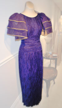 A purple silk chiffon gown with an accordion pleated skirt and three-tiered bell sleeves.