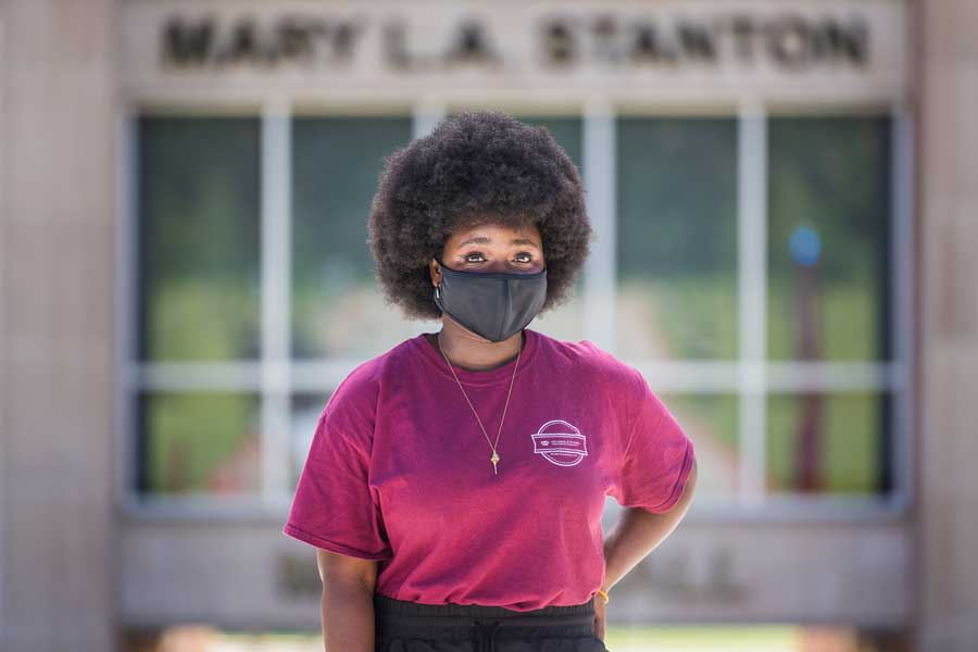 A TWU student and resident assistant wears a face mask on the Denton campus near Parliament Village.	