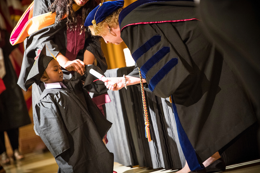small boy receives a diploma from TWU professor