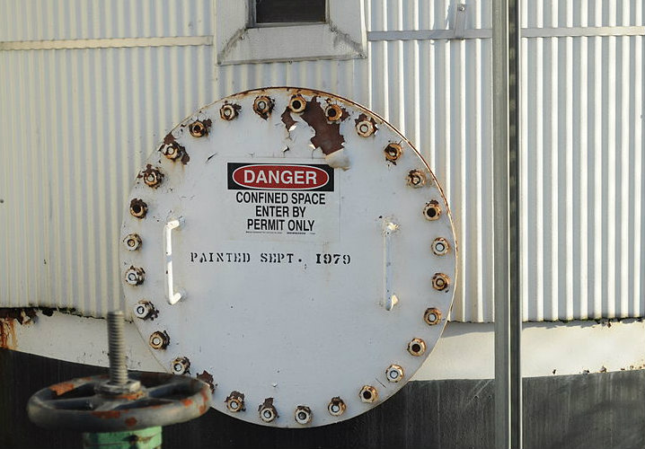 Warning sign on a silo door says "Danger confined space enter by permit only".