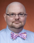 A photo of a man with glasses and a pink bowtie.